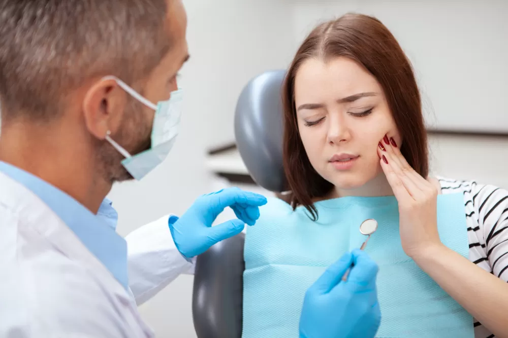 Young woman experiencing pain is being examined by a dental specialist