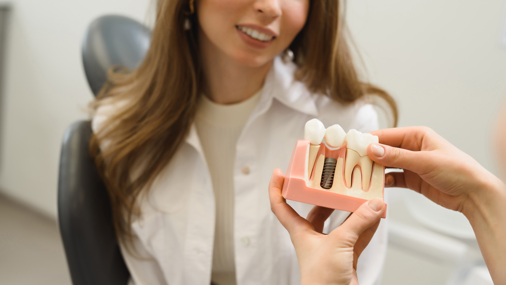 woman looking at a scale model of teeth implants