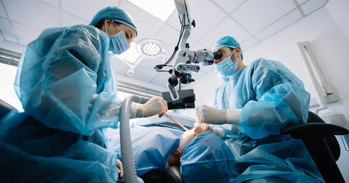 Two doctors performing oral surgery on a patient